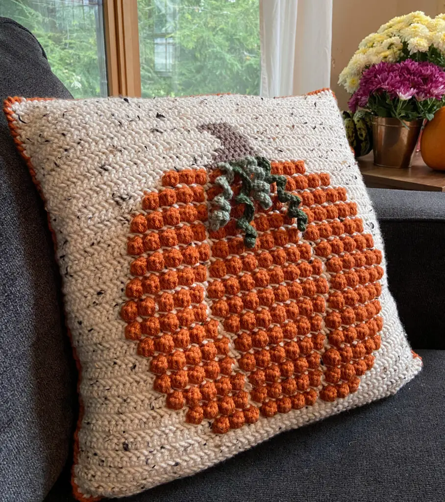 Fall Crochet Cushion on a couch with mums in the background